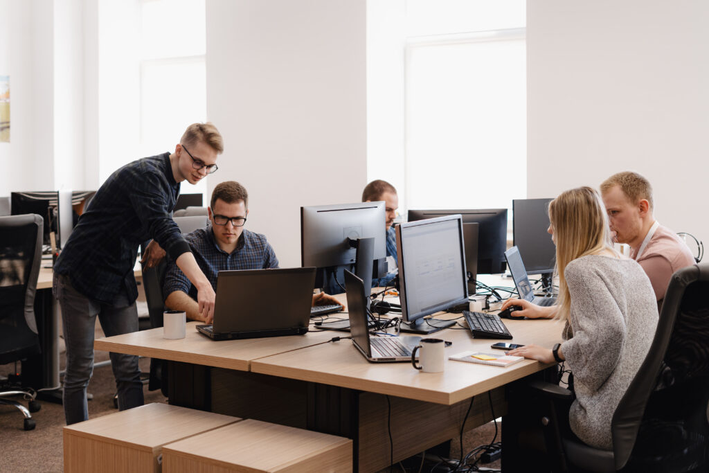 Full concentration at work. Group of young business people working and communicating while sitting at the office desk together with colleagues sitting in the background